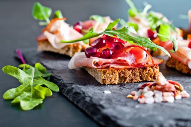 Otlar ve nar taneleri ile dilimlenmiş jambon