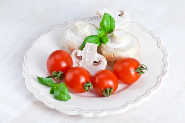 Tomatoes and mushrooms on white table — Stock Photo, Image