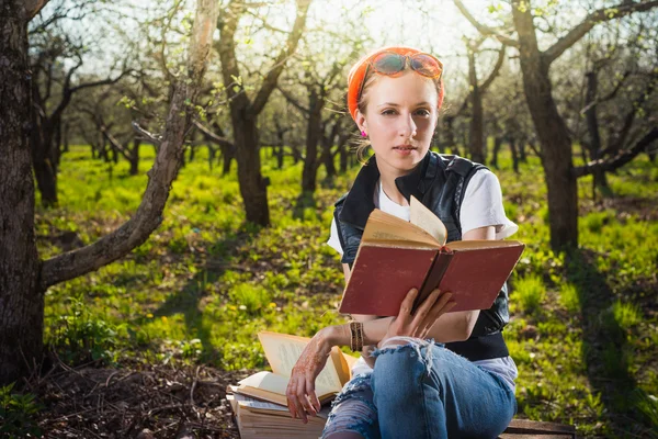 Woman in park outdoor with tablet and book deciding what to use — Stock Photo, Image