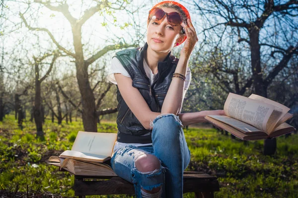 Woman in park outdoor with tablet and book deciding what to use — Stock Photo, Image