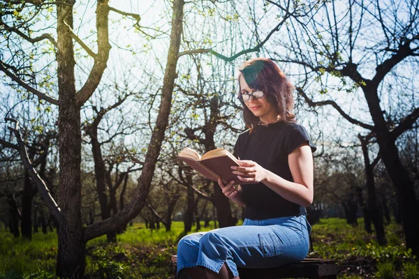 Woman in park outdoor with tablet and book deciding what to use — Stock Photo, Image