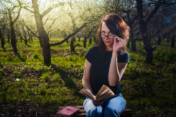 Woman in park outdoor with tablet and book deciding what to use — Stock Photo, Image