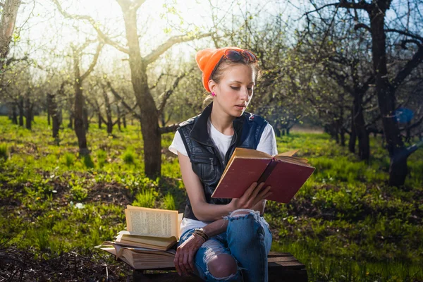 Woman in park outdoor with tablet and book deciding what to use — Stock Photo, Image