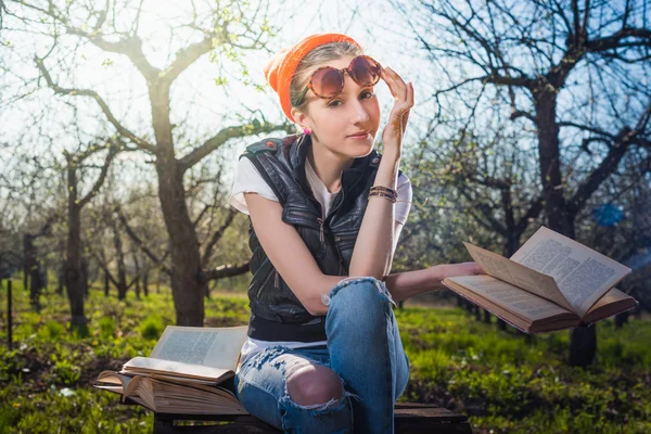 Woman in park outdoor with tablet and book deciding what to use — Stock Photo, Image