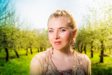 Bahçede elma ağacının yakınında duran güzel genç sarışın kadın