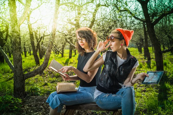 Woman in park outdoor with tablet and book deciding what to use — Stock Photo, Image