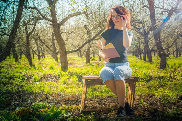 Woman in park outdoor with tablet and book deciding what to use — Stock Photo, Image