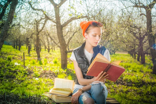 Woman in park outdoor with tablet and book deciding what to use — Stock Photo, Image