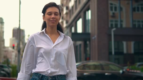 Glimlachende blanke vrouw loopt in de stad — Stockvideo