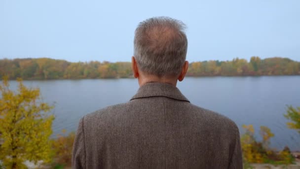 Senior visszapillantás pózol a folyóparton ősszel — Stock videók