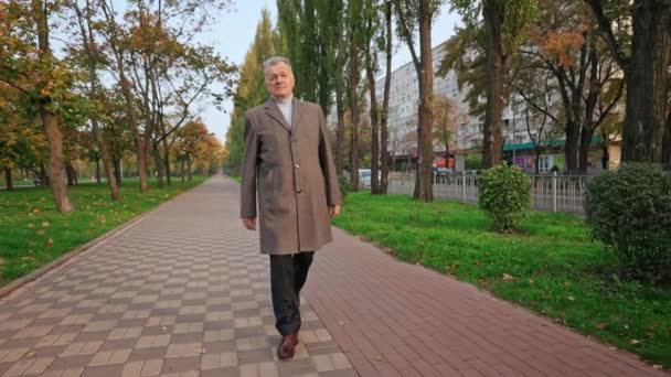 Alter grauhaariger Mann im Mantel geht auf die Straße — Stockvideo