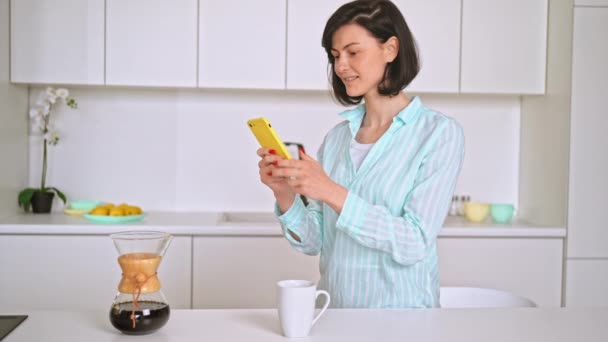 Feliz morena mulher bebendo café segurando smartphone — Vídeo de Stock