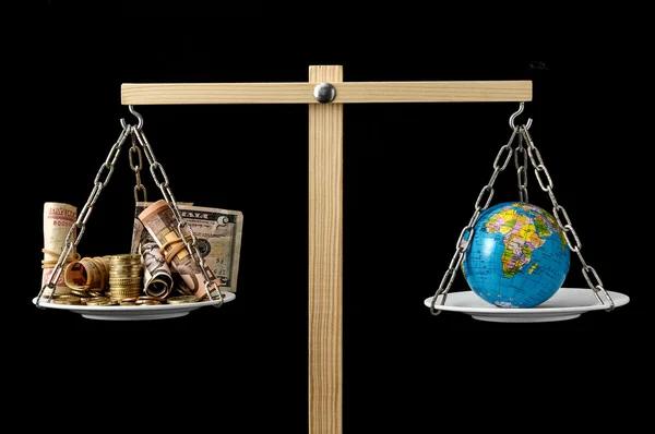 Aarde en geld op een twee pan balans — Stockfoto