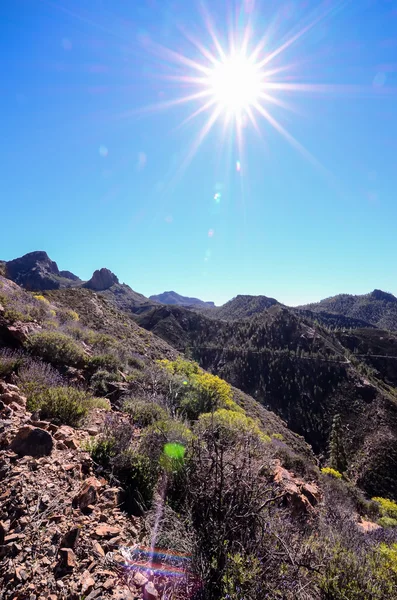 Sonnenstern am blauen Himmel über einer Bergsilhouette — Stockfoto