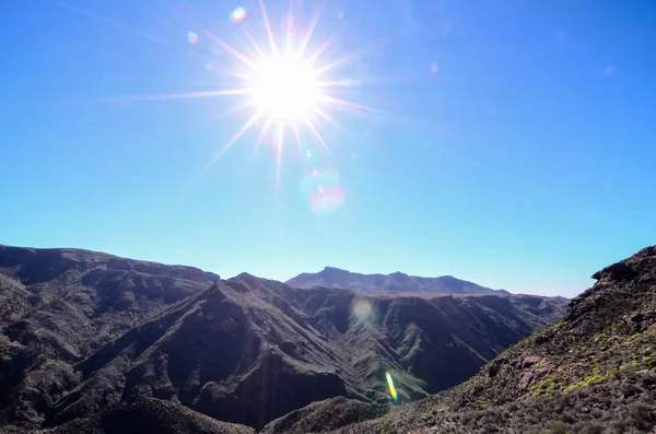 Sun Star sur un ciel bleu au-dessus d'une silhouette de montagne — Photo