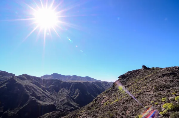 Sun Star sur un ciel bleu au-dessus d'une silhouette de montagne — Photo