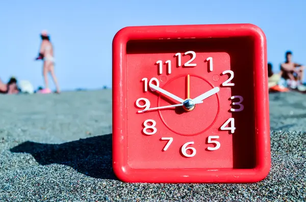 Klok op het zandstrand — Stockfoto