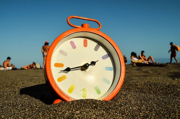 Klok op het zandstrand — Stockfoto