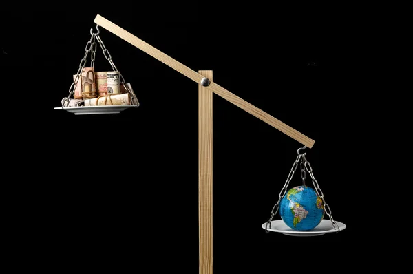 Aarde en geld op een twee pan balans — Stockfoto
