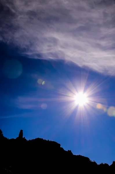 Sun Star på en blå himmel över en Mountain siluett — Stockfoto