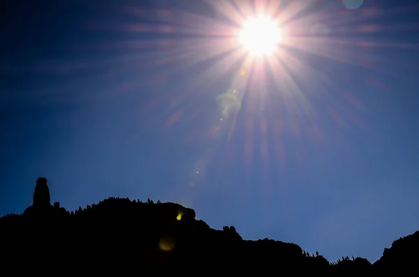 Sun Star sur un ciel bleu au-dessus d'une silhouette de montagne — Photo