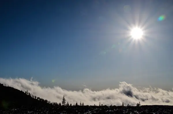 Солнечная звезда на голубом небе над силуэтом горы — стоковое фото
