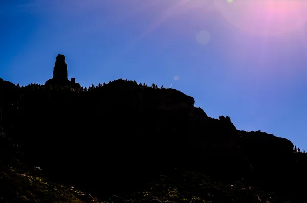 Sole stella su un cielo blu sopra una silhouette di montagna — Foto Stock