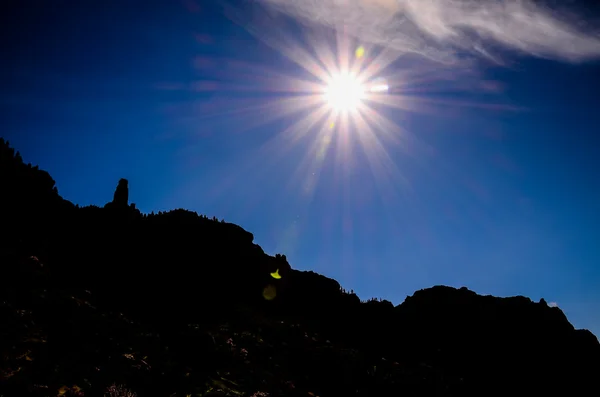 Sun Star sur un ciel bleu au-dessus d'une silhouette de montagne — Photo