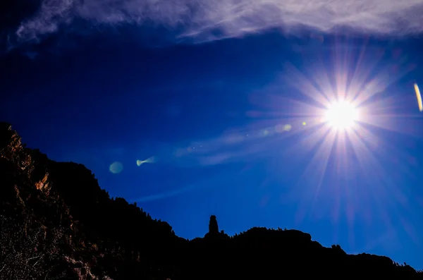 Sun Star op een blauwe hemel over een berg silhouet — Stockfoto