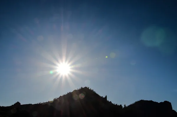 Sun Star sur un ciel bleu au-dessus d'une silhouette de montagne — Photo