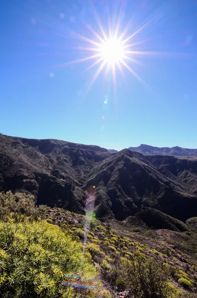 Sun Star sur un ciel bleu au-dessus d'une silhouette de montagne — Photo