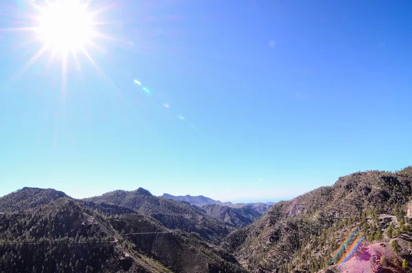 Sonnenstern am blauen Himmel über einer Bergsilhouette — Stockfoto