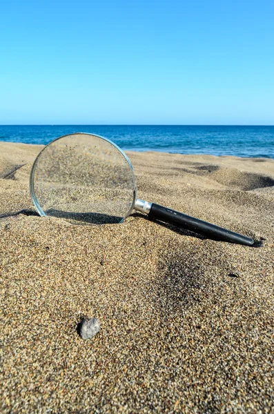 Zvětšit sklo na písečné pláži — Stock fotografie