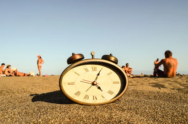 Klok op het zandstrand — Stockfoto