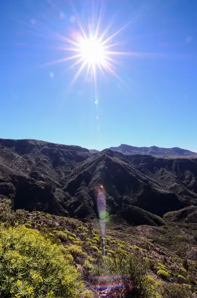 Sun Star sur un ciel bleu au-dessus d'une silhouette de montagne — Photo