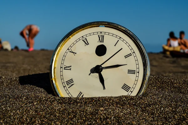 Klok op het zandstrand — Stockfoto