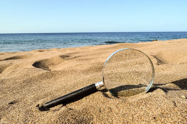 Zvětšit sklo na písečné pláži — Stock fotografie