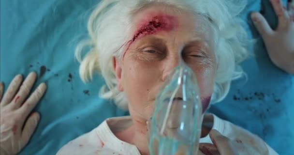 パルスをチェックし、負傷した老婦人酸素マスクを置く救急車のビューを閉じます。病院のストレッチャーの上で寝そべっている間に熟女が死んでいく。事故の概念. — ストック動画