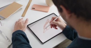 Not kağıdında illüstrasyon yaratırken erkek ressamın kuşun omuz manzarası üzerinde. Guy grafik çizer masada otururken dijital ped ve stil kullanır. Modern sanat kavramı.