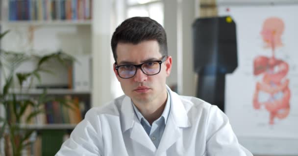Crop view of serious man in glasses and white professional coat shaking head and looking to camera in medical office. Doctor listening patient having online consultation. Telehealth. — Stock Video