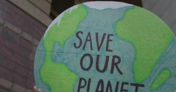 Вид на урожай человека, воспитывающего модель Земли с помощью письма, спасает нашу планету. Женщины держат плакат, когда бьют по загрязнению окружающей среды. Концепция экологии. — стоковое видео
