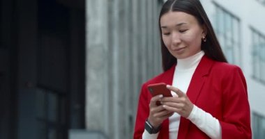 Akıllı telefon kullanarak ekranı kaydıran ve dokunan neşeli iş kadını. Şehir caddesinde dikilirken telefona bakan çekici bir kadın. Başarılı insanlar kavramı.