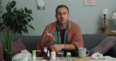 30 'lu yaşlardaki hasta adam doktorla konuşurken tıptan ve kameraya bakmaktan bahsediyor. Genç adam battaniyeyle örtülmüş kanepede otururken sağlık görevlisiyle internet üzerinden iletişim kuruyor..