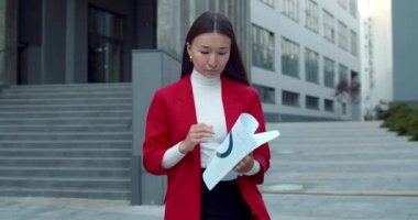 Yoğunlaştırılmış Asyalı iş kadını, iş yerindeki iş yerlerindeki çalışma belgelerine bakıyor. Dışarıda yürürken gazete okuyan başarılı stil sahibi bir kadın..