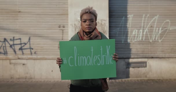 Lwów, Ukraina - 27 listopada 2019: Afro amerykańska kobieta stojąca na ulicy i trzymająca napis pikietowy z napisem o strajku klimatycznym. Koncepcja zmiany klimatu i globalnego ocieplenia. — Wideo stockowe