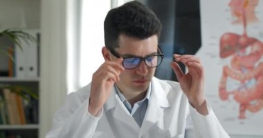 Genç erkek doktorun gözlük ve masaj yapan gözlerini çıkardığı ekin manzarası. Profesyonel soygun yapan beyaz adam, sağlık odasında masada otururken yorgun görünüyor. Aşırı çalışma kavramı.