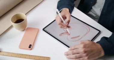 Erkek web tasarımcısının dijital tablette elma çizimi yaptığı en üst görünüm. Talanted adam masasında otururken ve resim üzerinde çalışırken ped ve stil kullanıyor..