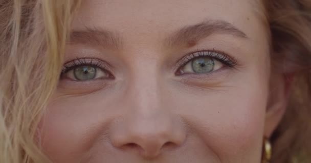 Porträtt av attraktiv kvinnlig modell ansikte tittar på kameran. Närbild av ung kvinna med kort blont hår och ljusgröna ögon ler. Begreppet livsstil. suddig grön bakgrund. — Stockvideo