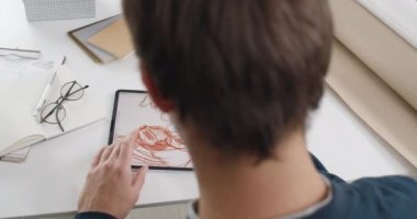 Erkek web tasarımcısının dijital tablet üzerinde resim çizimi yaparken omuz hizasında. Masasında oturup proje üzerinde çalışırken ped ve stil kullanan Talanted adam.