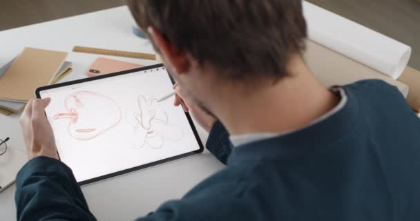 Sobre a visão do ombro do artista fmale desenho ilustração no tablet enquanto sentado no local de trabalho. ilustrador gráfico usando almofada digital e estilete durante o esboço. Conceito de arte. — Vídeo de Stock